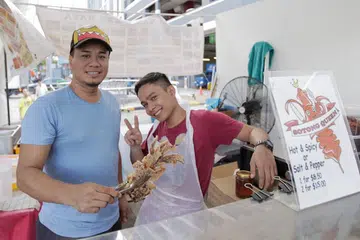 PELBAGAI PILIHAN: Selain daripada Sotong Goreng, Kek Lapis Sarawak dan Tapak Kuda dijual di gerai yang dikendalikan Daily Makan & Events. Am Cha (kiri) dan Danny (kanan), pekerja di Gerai Daily Makan & Events. - Foto BH oleh IQBAL FAISAL