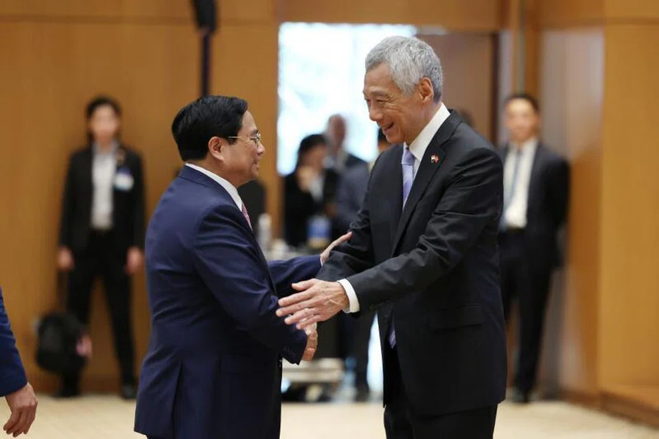 PERTEMUAN MESRA:  Perdana Menteri, Encik Lee Hsien Loong (kanan), berjabat mesra dengan Perdana Menteri Vietnam, Encik Pham Minh Chinh, semasa menghadiri Sidang bagi Menggalak Pelaksanaan Projek Kerjasama Vietnam-Singapura di Pejabat Pemerintah Hanoi pada Selasa.
