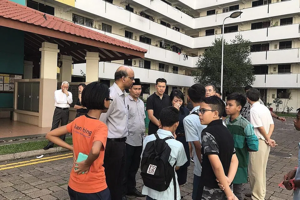 TURUT KONGSI DUKACITA: Encik Tharman (dua dari kiri) mengunjungi keluarga Allahyarham Muhammad Suhaimi di rumah mereka semalam. Beliau turut menemui beberapa teman Allahyarham di kolong blok flat tersebut di Ho Ching Road. - Foto THE STRAITS TIMES
