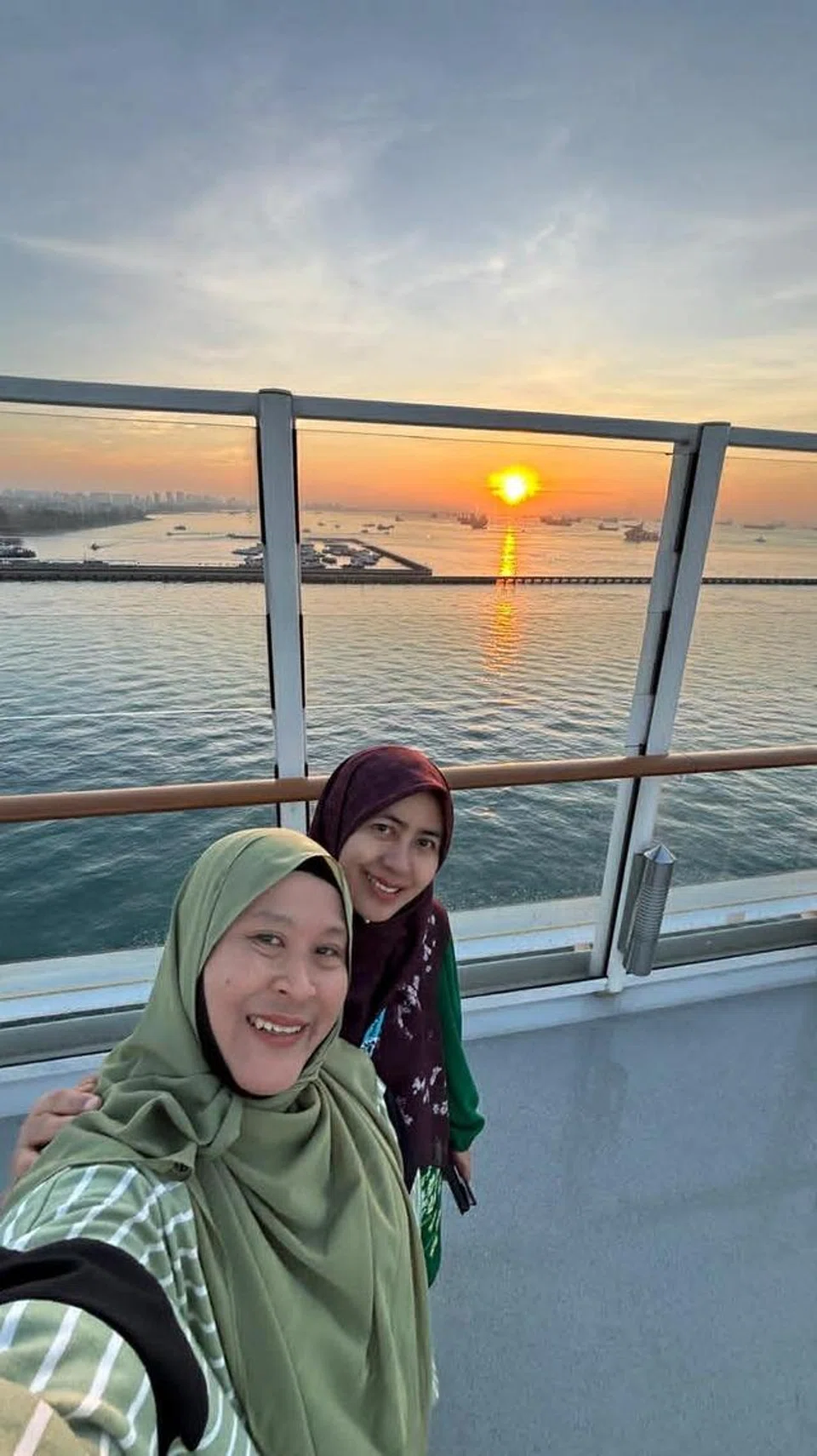Cik Azhanani Kamis (kanan) bergambar berlatarbelakangkan matahari terbit di atas kapal bersama sahabatnya, Suliha Yusoff.