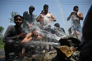 MENYEJUKKAN BADAN: Beberapa lelaki di pancuran air di tepi jalan  semasa cuaca panas di Islamabad baru-baru ini. -. (Photo by Farooq NAEEM / AFP)