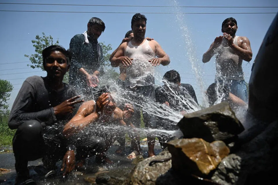 MENYEJUKKAN BADAN: Beberapa lelaki di pancuran air di tepi jalan  semasa cuaca panas di Islamabad baru-baru ini. -. (Photo by Farooq NAEEM / AFP)