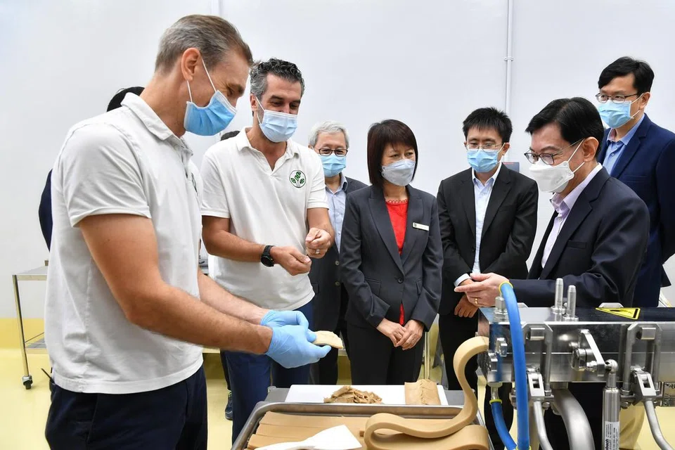 INOVASI MAKANAN: Ketua pengeluaran SGProtein, Encik Bernhard Schiele (kiri), serta CEO dan pengasas bersama SGProtein, Encik Dominique Kull (dua dari kiri), menunjukkan kepada Encik Heng Swee Keat (depan kanan) cara mesin penyemperitan berfungsi semasa pelancaran kilang FoodPlant semalam.