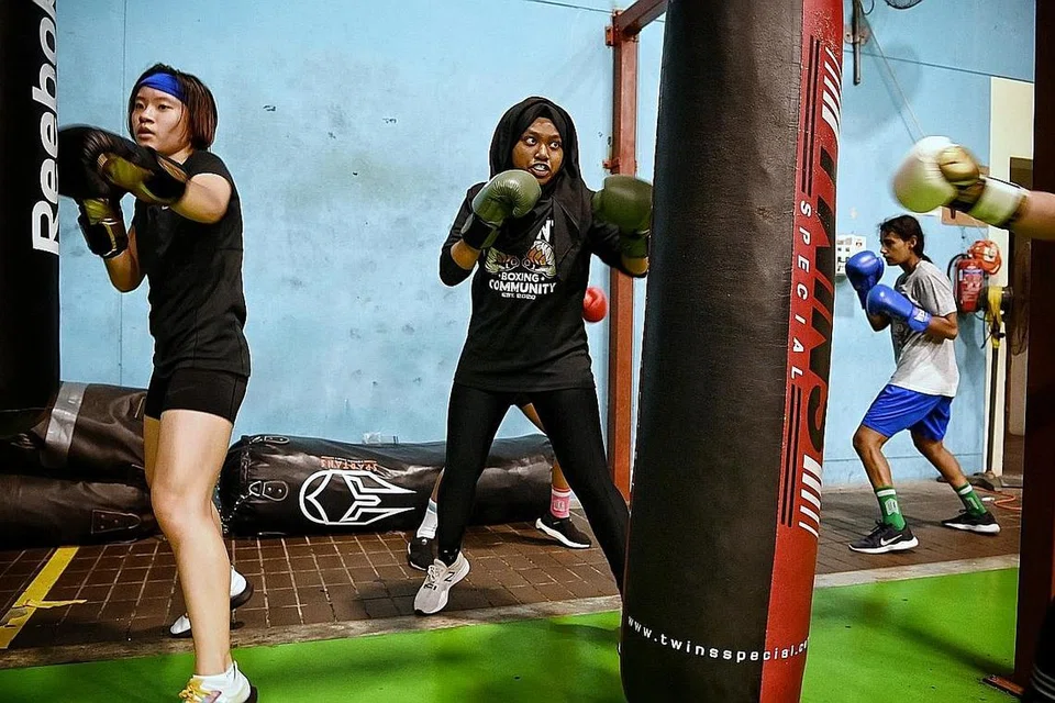 MAHU TUNJUK TARING DI GELANGGANG: Selepas sekali masuk gelanggang bertinju, minat Amirah Razak (atas, kanan) pada sukan tinju mekar dan beliau kini menjadi anggota pasukan pembangunan tinju wanita amatur Singapura yang berlatih di Dewan Sukan Bedok dibawah bimbingan jurulatih Muhamad Ridhwan. - Foto-foto BH oleh KUA CHEE SIONG