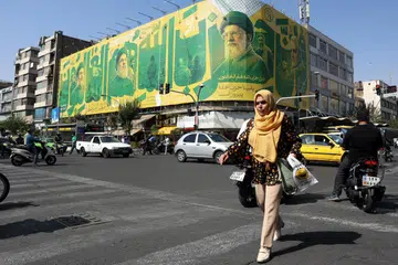 Seorang wanita Iran berjalan di hadapan papan iklan memaparkan gambar Allahyarham Pemimpin Tertinggi Iran, Ayatollah Ali Khamenei (tengah), dan pemimpin Hamas di Teheran, Iran, pada 6 Oktober 2026. Ketegangan Amerika Syarikat-Iran berterusan ketika Rumah Putih dilaporkan meminta Pentagon menyediakan pilihan bagi kemungkinan serangan baru ke atas Iran.