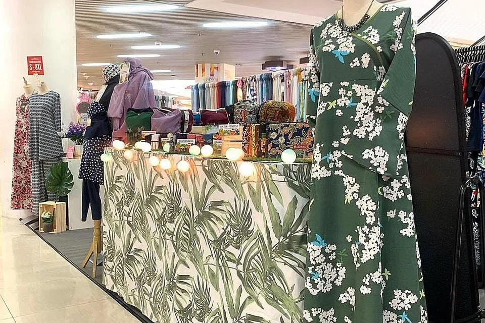 MENGUBAH STRATEGI: Pemilik Ilham Empire, Cik Nur Asyiqin Jumato bergambar bersama tukang jahitnya di sebuah kilang di sekitar kawasan Batam Centre, Batam, Indonesia. Beliau akan menjual bekalan pakaiannya di gerai yang disewanya di pusat beli-belah Causeway Point (gambar atas). - Foto-foto ILHAM EMPIRE