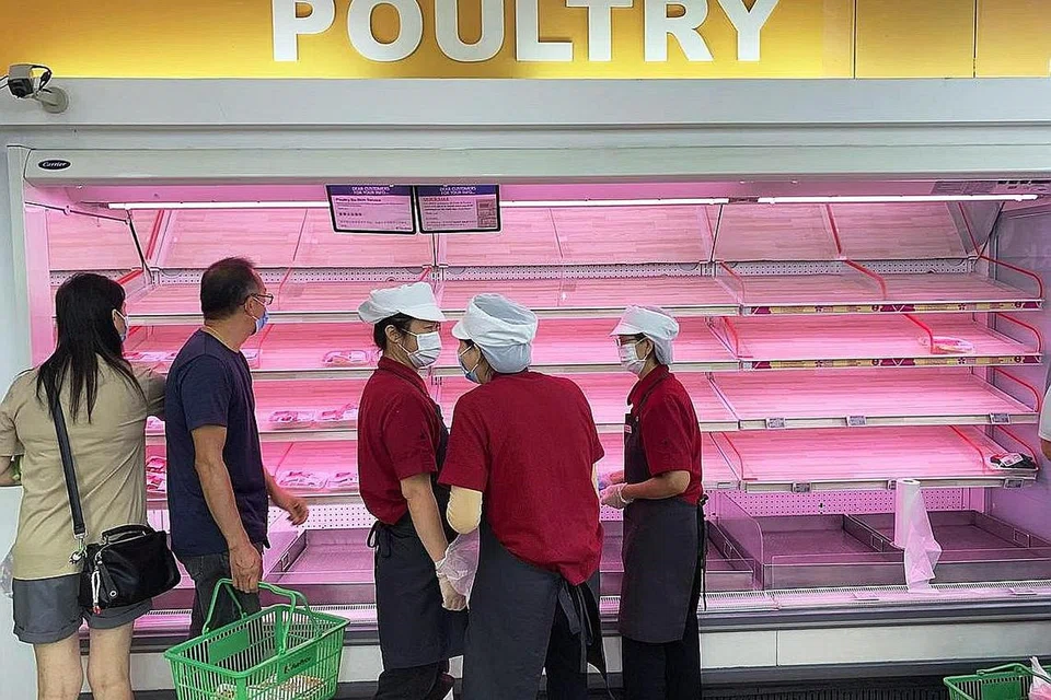 BEKALAN AYAM HABIS DIJUAL: Empat rak-rak jualan ayam di pasar raya cawangan FairPrice di Bedok Central kosong dengan serta-merta apabila ramai pelanggan berebut membeli lebih banyak daripada biasa. - Foto BH oleh RYAN GOH
