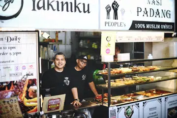 Encik Ismail Didih Ibrahim (kiri) kini menguruskan gerai ‘People’s Nasi Padang’ dan ‘Rio Yakiniku’ di 61 Tai Seng Avenue, menggajikan bekas pesalah seperti Encik Nizam Dardari (kanan) bagi mereka meraih pengalaman dan kemahiran menguruskan cawangan makanan dan minuman (F&B).