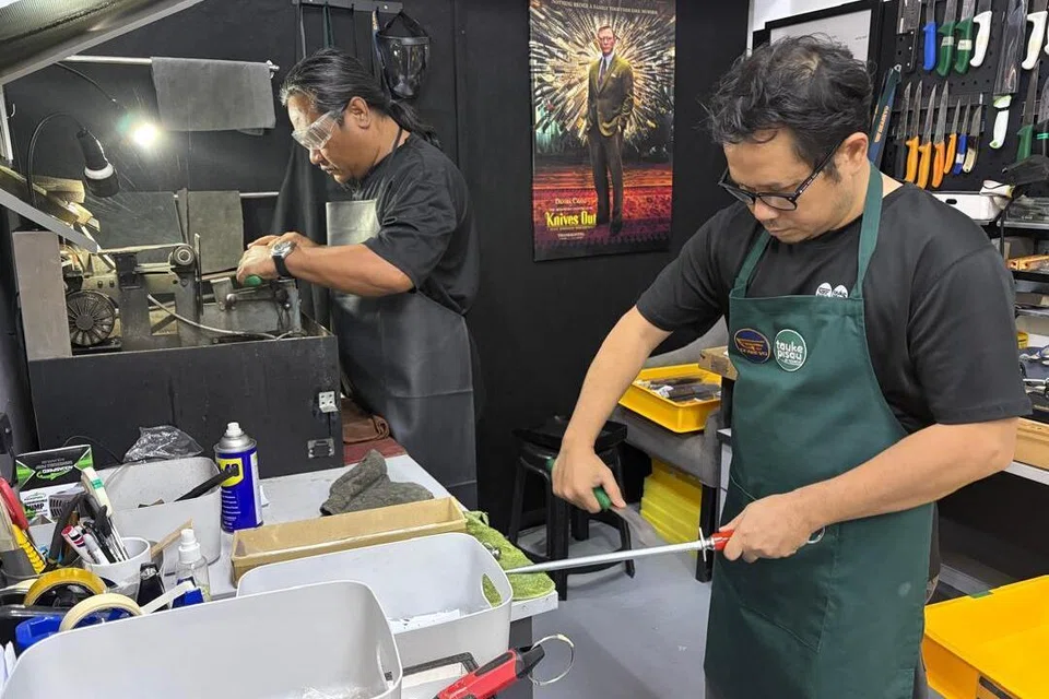 Encik Kamarulzaman Hashim (kiri) dan Pengurus Pengeluaran di Tauke Pisau by Gearevo, Encik Amir Ridhwan Mohd Ghazali, tekun melakukan tugas mengasah pisau.