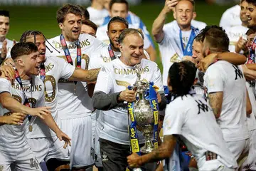 KEMUNCULAN YANG DINANTI: Pengurus Leeds United Marcelo Bielsa (memegang trofi) semasa meraikan kemenangan pasukannya dalam Liga Championship Julai lalu dan sekali gus dinaikkan ke EPL. Bielsa akur berdepan ujian sukar di Anfield awal pagi esok iaitu perlawanan Liga Perdana pertama kelab itu dalam 16 tahun. - Foto REUTERS