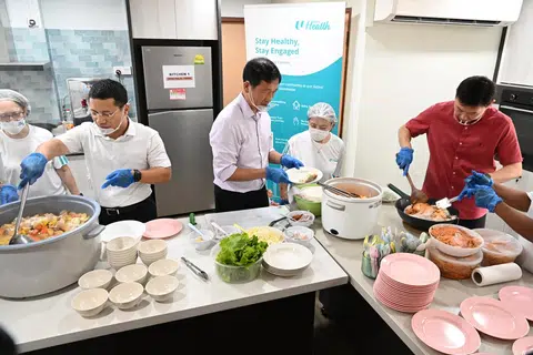 MENTERI SEDIA KE DAPUR: (Dari kiri) Menteri Pembangunan Negara, Encik Desmond Lee; Menteri Kesihatan, Encik Ong Ye Kung; dan Pemangku Menteri Pengangkutan, Encik Chee Hong Tat bantu warga emas memasak di Dapur Komuniti Kesihatan NTUC di Lengkok Bahru pada Khamis.