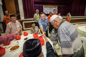 SEMANGAT RAMADAN: Encik Zaqy beramah mesra sambil mengagihkan habuan Hari Raya kepada seramai 179 penduduk memerlukan dalam majlis berbuka puasa semalam. - Foto CCC MARSILING