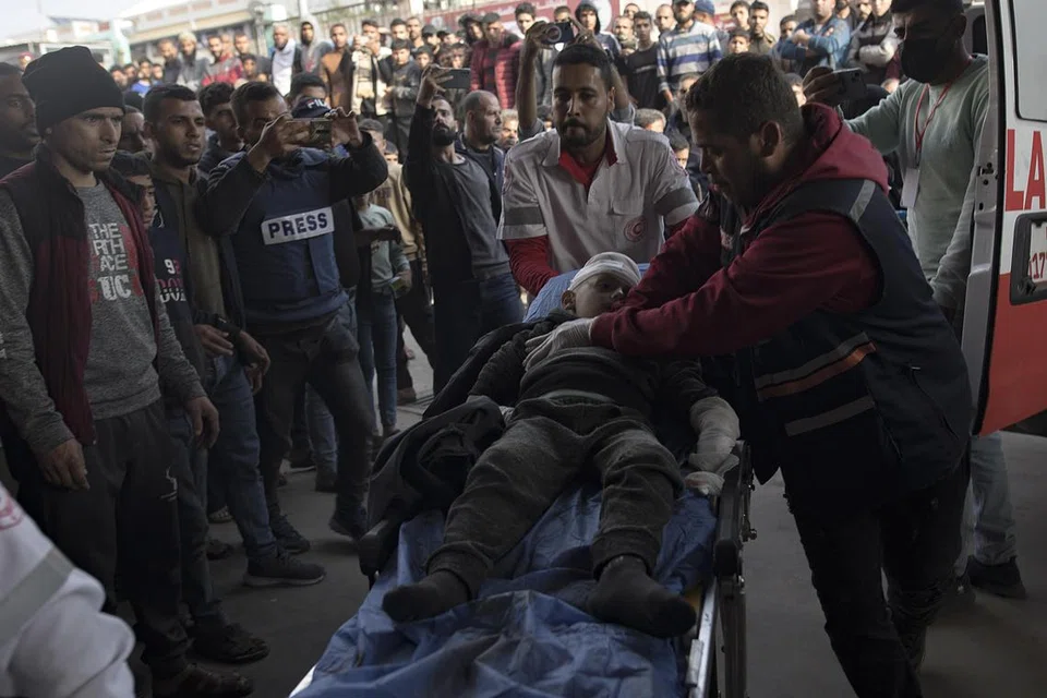 SEDANG DISELAMATKAN: Seorang pegawai medik Hospital Nasser, di Khan Younis, cuba menyelamatkan seorang kanak-kanak yang cedera akibat pengeboman Israel pada 27 Disember. Banyak hospital di Gaza yang kini lumpuh akibat kekurangan ubat-ubatan dan terlalu ramai pesakit perlu dirawat.