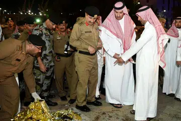 DALANG DIBERKAS: Gambar dipetik pada 4 Julai ini menunjukkan Datuk Bandar Madinah, Encik Faisal bin Salman bin Abdulaziz (dua dari kanan) dan pegawai keselamatan meninjau kesan-kesan darah selepas serangan bunuh diri di luar ibu pejabar pasukan keselamatan berhampiran Masjid Nabawi. - Foto AFP