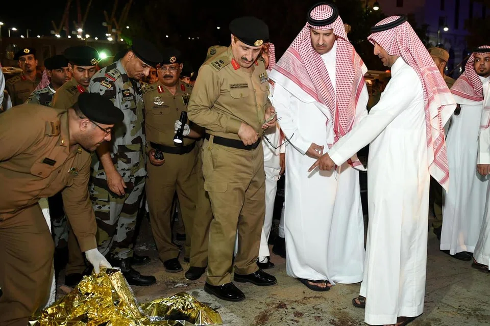 DALANG DIBERKAS: Gambar dipetik pada 4 Julai ini menunjukkan Datuk Bandar Madinah, Encik Faisal bin Salman bin Abdulaziz (dua dari kanan) dan pegawai keselamatan meninjau kesan-kesan darah selepas serangan bunuh diri di luar ibu pejabar pasukan keselamatan berhampiran Masjid Nabawi. - Foto AFP