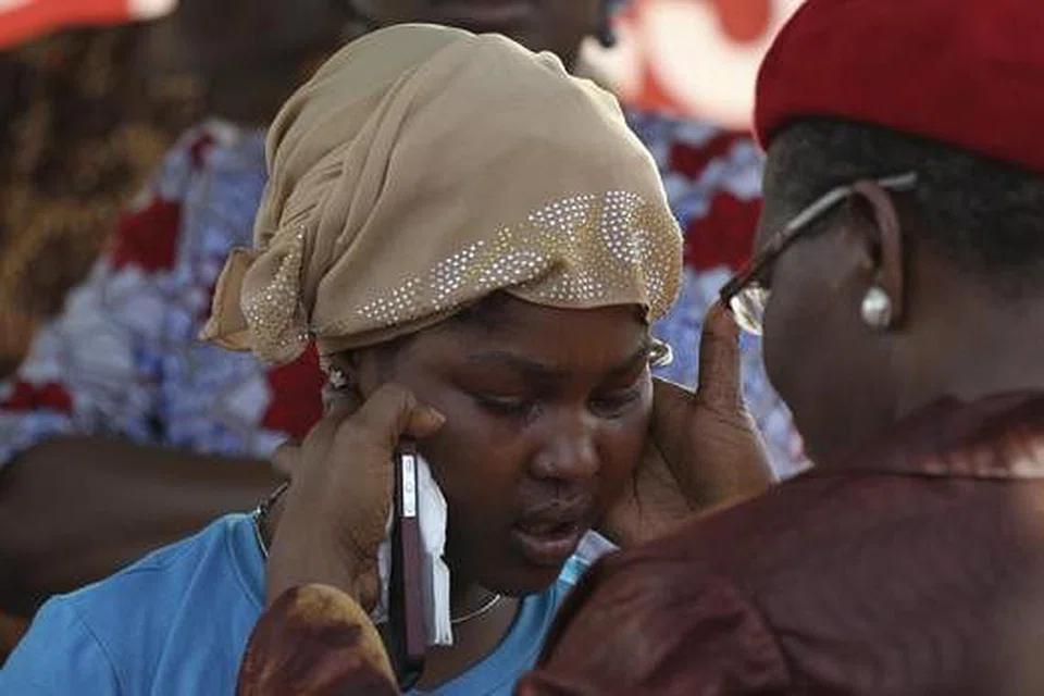 MENGENANG NASIB PELAJAR YANG DICULIK BOKO HARAM: Seorang pembantah terhadap penculikan 276 pelajar perempuan sekolah berasrama di Chibok, timur laut Nigeria, yang kesedihan ditenangkan oleh Encik Obiageli Ezekwesili, bekas naib presiden Bank Dunia divisyen Afrika (kanan), di Unity Fountain di Abuja pada 15 Mei lalu. - Foto REUTERS