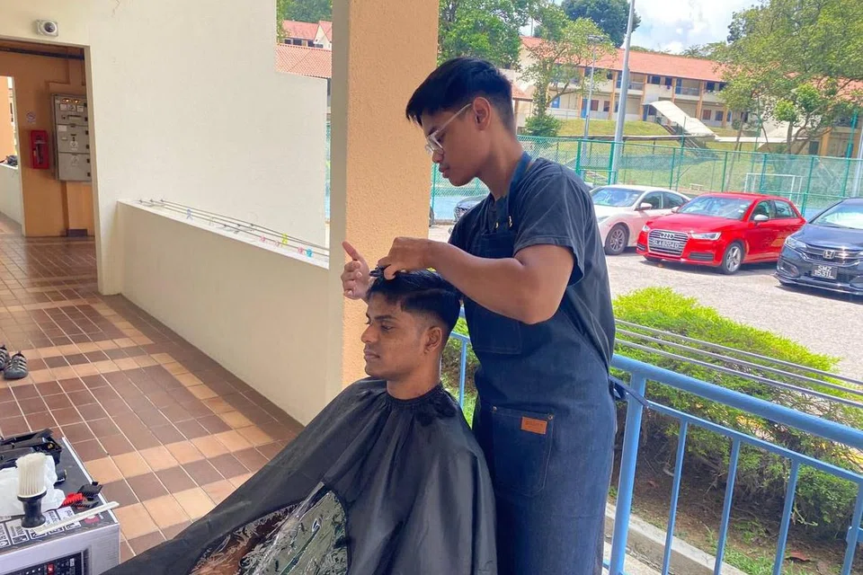TUKANG GUNTING RAMBUT: Encik Muhammad Afif Kamaludin (berdiri), mahasiswa NTU, 23 tahun, yang tinggal di ‘Hall 2’ menggunting rambut rakan asrama untuk mendapat lebih wang perbelanjaan.