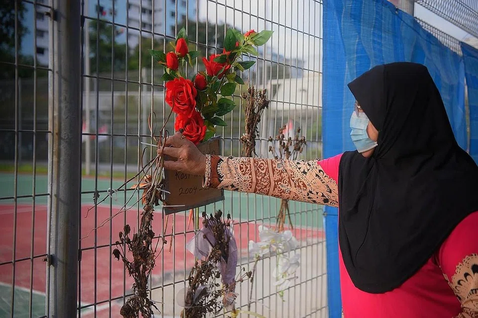 KENANG ANAK TERSAYANG: Cik Rahimah Lee Abdullah di gelanggang bola keranjang di mana anaknya, Mohd Ridwan, meninggal dunia setelah struktur papan bola keranjang jatuh menimpanya pada Julai lalu. Beberapa orang awam meninggalkan bunga di sana. - Foto BH oleh MARK CHEONG