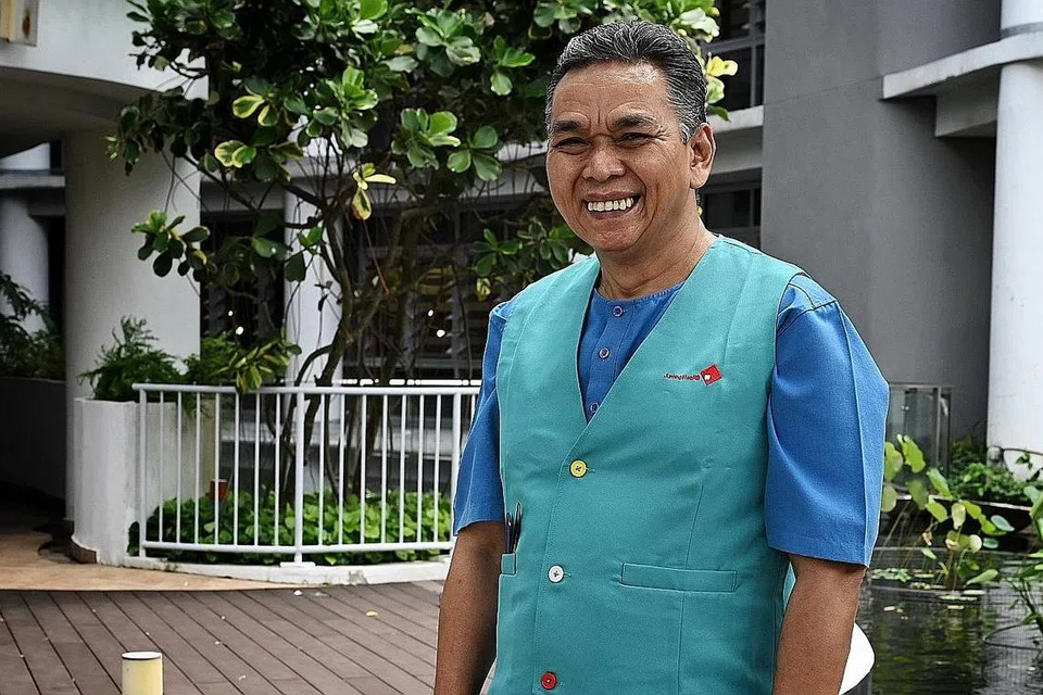 GUNTING RAMBUT: Sebulan sekali, Encik Taha meluangkan masa di Hospital Masyarakat Jurong untuk menggunting rambut pesakit yang tinggal di sana untuk jangka masa panjang. Menunjukkan Encik Taha sedang menggunting rambut seorang pesakit. - Foto-foto BH oleh MOHD KHALID BABA