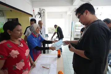 TIDAK CEMAS ATAU PANIK: Penduduk mengambil pelitup percuma di pusat Jawatankuasa Penduduk di Blok 47 Telok Blangah Drive semalam. - Foto BH oleh TIMOTHY DAVID