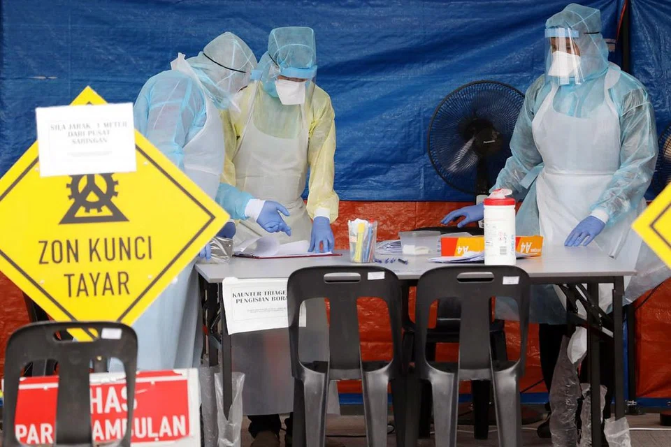 PEMERIKSAAN DIPERLUAS: Beberapa pekerja kesihatan dengan alat pelindung peribadi sedang bertugas di satu perkhemahan yang ditubuhkan sebagai pusat pemeriksaan di satu klinik di Kuala Lumpur pada 23 Mac 2020. - Foto REUTERS. 