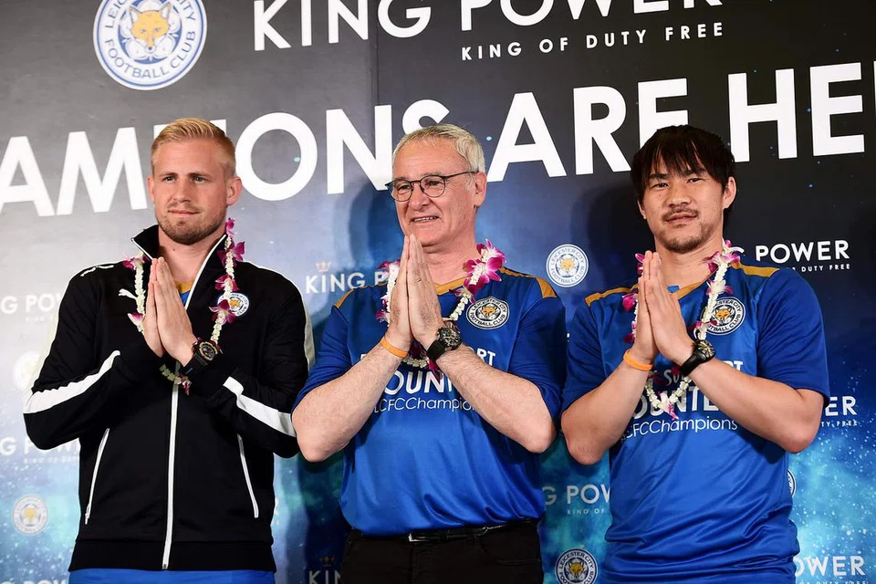 BERI SAMBUTAN HANGAT: Pengurus Leicester City Claudio Ranieri (tengah), yang diapit Kasper Schmeichel (kiri) dan Shinji Okazaki (kanan), memberi salam 'ala Thai' setibanya mereka di Lapangan Terbang Antarabangsa Suvarnabhumi, Bangkok, semalam. - Foto REUTERS
