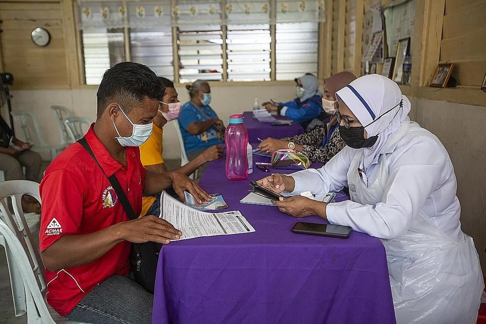 USAHA PERANG PANDEMIK: Seorang jururawat memeriksa dokumen seorang penduduk kampung sebelum beliau diberi suntikan vaksin Covid-19 di Banting, dekat Kuala Lumpur, 8 Julai lalu. - Foto EPA-EFE