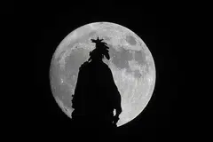 BULAN PALING BESAR: 'Supermoon' yang dilihat di sebalik Statue of Freedom di Capital Dome di Washington, DC, pada malam Ahad lalu. Bulan penuh itu berada di jarak paling dekat dengan bumi sejak 68 tahun lalu malam tadi dengan hanya sekitar 356,500 kilometer antara bulan dengan bumi. - Foto AFP