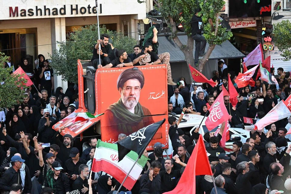 Orang ramai berhimpun di sebuah jalan di Mashhad, Iran, pada 9 Julai 2026 ketika upacara pengebumian bekas Pemimpin Tertinggi Iran, Ayatollah Ali Khamenei, sambil berlatarbelakangkan potret penggantinya, Mojtaba Khamenei. Mojtaba, yang mengambil alih jawatan selepas kematian bapanya, terus menjadi perhatian kerana tidak pernah muncul di khalayak sejak dilantik, sekali gus mencetuskan spekulasi mengenai keadaan dan peranannya dalam kepimpinan Iran ketika negara itu berdepan konflik dengan Amerika Syarikat dan Israel.