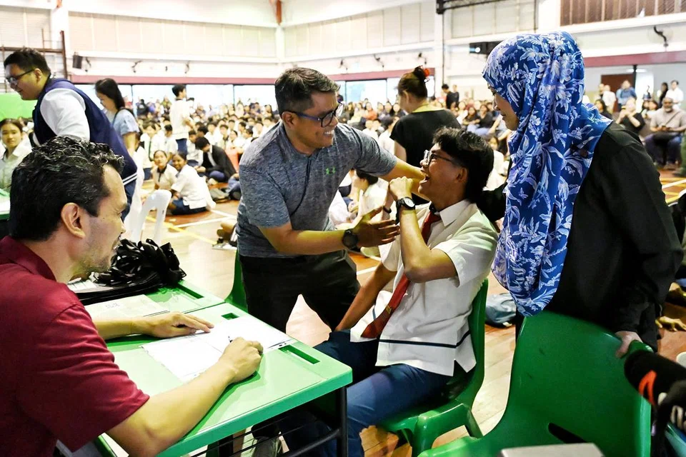 Pelajar Sekolah Menengah Fuchun, Muhammad Aman Ramdzan (tengah), meraikan pencapaiannya bersama ayahnya, Encik Ramdzan Abdul Rahman, dan ibunya, Cik Zuriah Jemani, semasa mengambil keputusan peperiksaan Sijil Am Pelajaran (GCE) Peringkat ‘O’ pada 10 Januari.