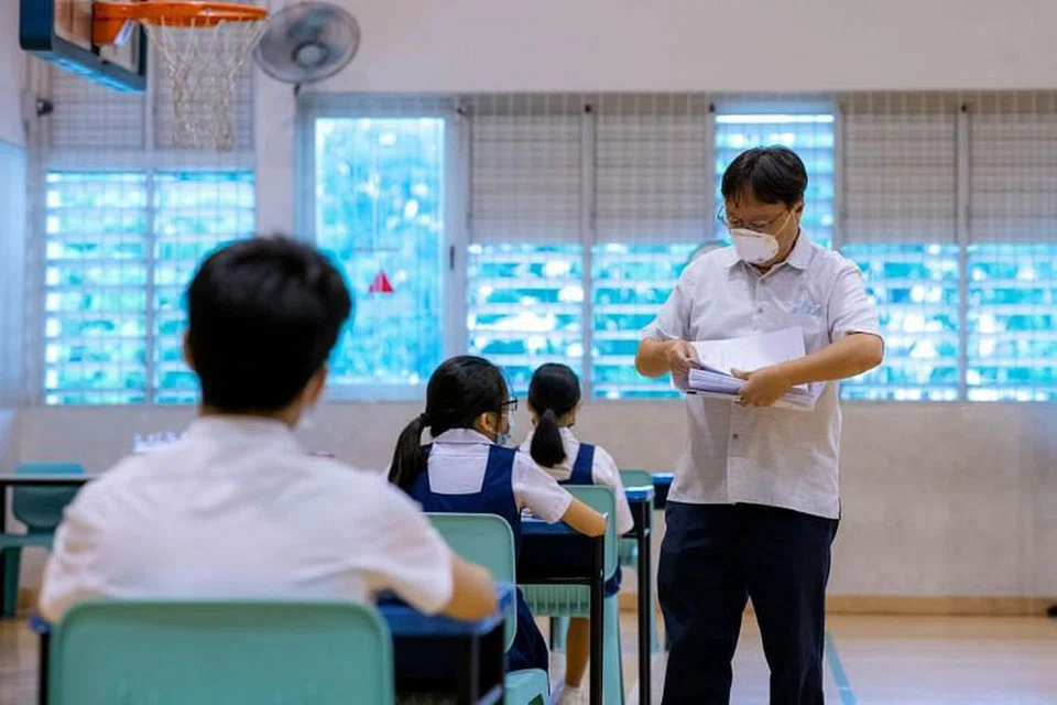 Pengawas memberi kertas ujian di ruang peperiksaan untuk pelajar yang dikuarantin.