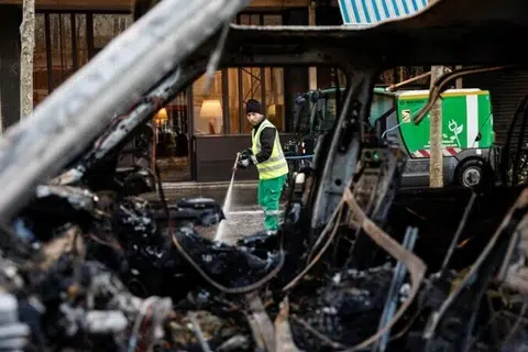 Seorang pekerja pihak berkuasa tempatan membersihkan jalan pada 18 Oktober, sehari selepas tunjuk perasaan itu, dilihat menerusi sebuah kereta yang hangus terbakar.