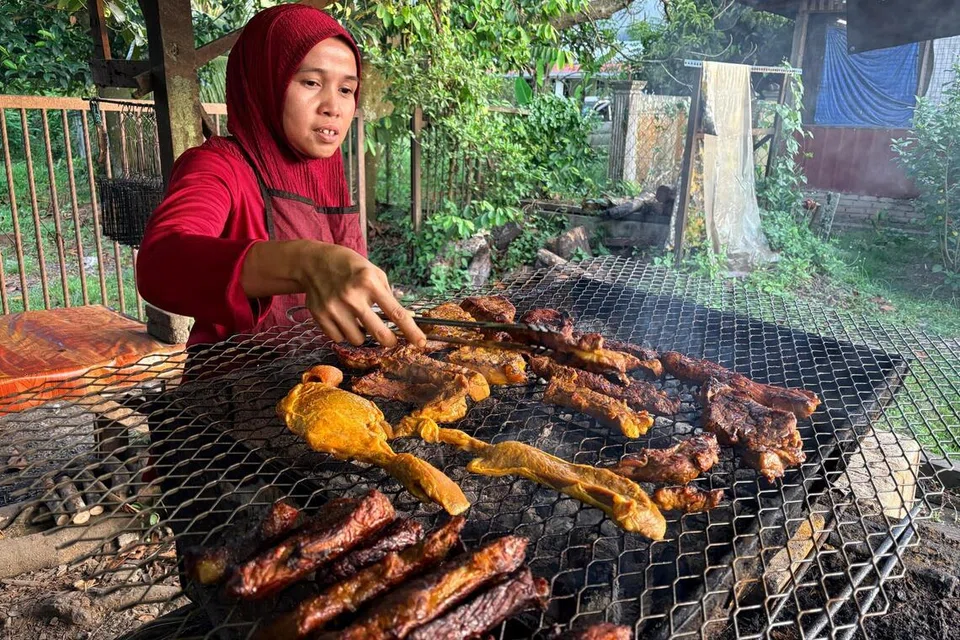 Cik Noraziah Muhamad, menyediakan daging salai permintaan pelanggan di gerainya di Jalan Seremban-Kuala Pilah berhampiran Terachi, Kuala Pilah, Negeri Sembilan.