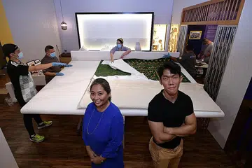 ANJUR PAMERAN: Kurator Cik Suhaili Osman (kiri) dan Encik Nasri Shah (kanan) sibuk dengan persiapan pameran Urang Banjar di Taman Warisan Melayu (TMW). Di belakang adalah artifak dinding arguci, yang digantung di pelamin perkahwinan masyarakat Banjar. - Foto BH oleh NG SOR LUAN