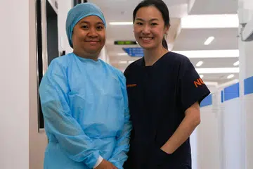 GEMBIRA BERTUGAS: Cik Julia Tubari (kiri), pembantu pembedahan gigi di Jabatan Pergigian Hospital Universiti Nasional (NUH), menganggap hubungan yang terjalin antara pesakit dengan doktor seperti Dr Tan Mei Na (kanan), pendaftar Jabatan Pergigian NUH, menandakan kepercayaan yang membuatnya berasa gembira dan menjadi dorongan kepadanya semasa bertugas. - Foto BM oleh SAHIBA CHAWDHARY