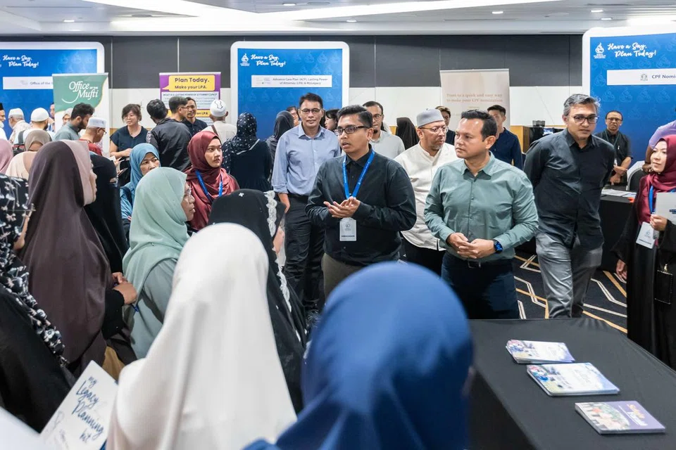 Eksekutif Kanan Unit Dana Masyarakat Muis, Encik Sulaiman Suradi, (tengah), berkongsi penerangan tentang inisiatif Wakaf Masyarakat Singapura (WMS) kepada para pengunjung di Perkampungan Legasi 2024, turut diperhatikan oleh Menteri Negara Kanan (Pertahanan serta Kemampanan dan Sekitaran), Encik Zaqy Mohamad, yang berada di sisinya.