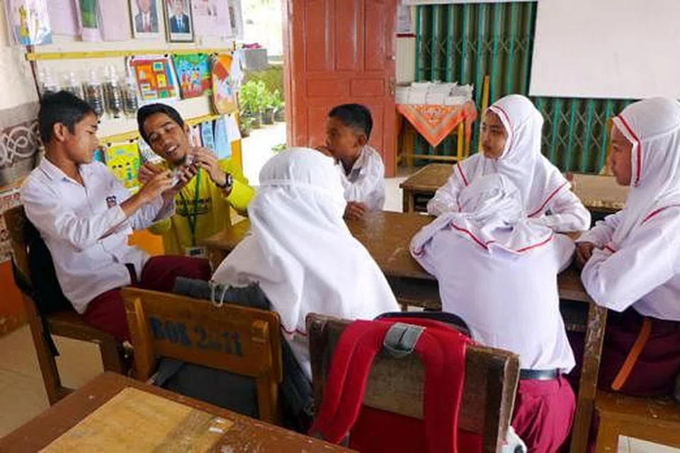 AMALKAN KEBERSIHAN: Relawan, Encik Muhammad Nur Aizat (dua dari kiri), yang juga pelajar perubatan NUS, bersama pelajar di Sumatera menerangkan pentingnya menjaga kesihatan.