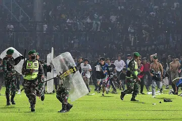 RUSUHAN: Penyokong Arema FC berlari di atas padang ke arah anggota tentera Indonesia selepas perlawanan bola sepak antara Arema FC dan Persebaya di stadium Kanjuruhan di Malang, Jawa Timur. - Foto AFP
