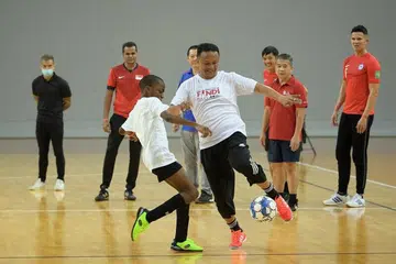 Fandi Ahmad dan seorang pemain bawah 10 tahun sedang beraksi dalam satu perlawanan pameran pada 18 Jun.