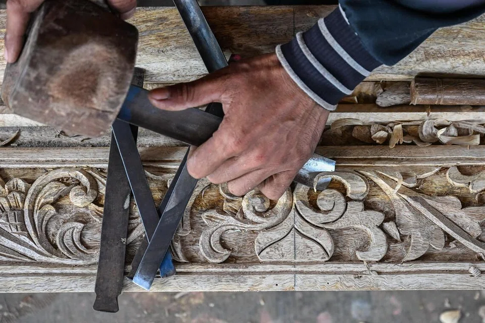 Seorang petukang mengukir rangka kayu yang menjadi pemegang alat muzik, memahat kayu bagi menghasilkan corak hiasan.