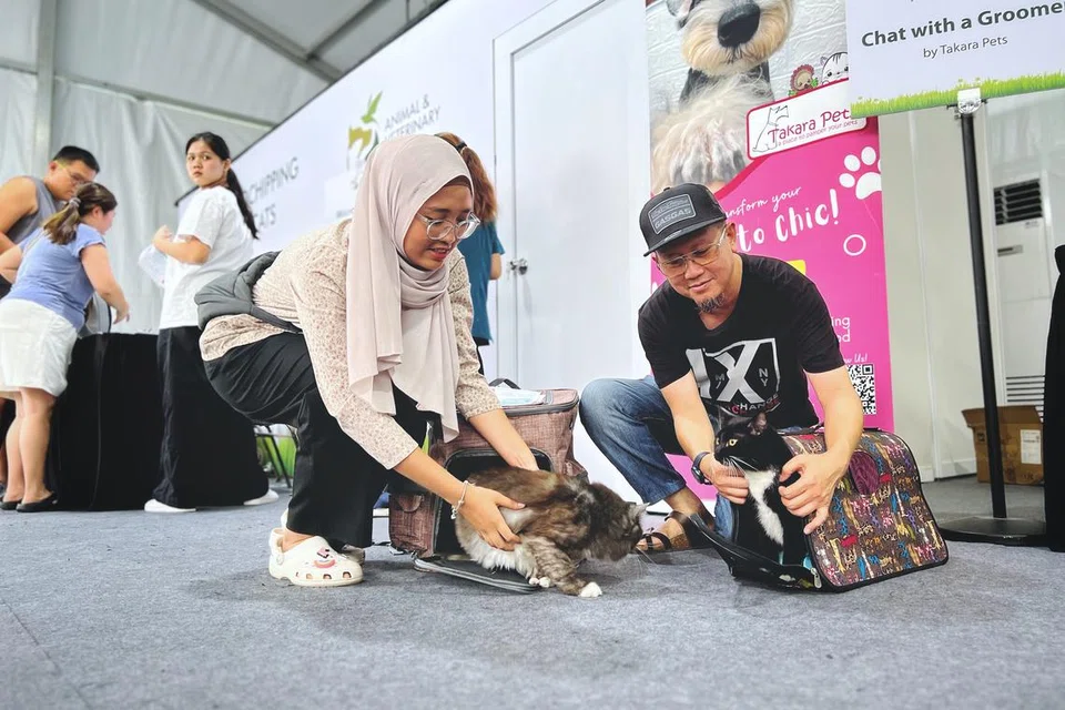 Encik Nasrul Md Suhud (kanan) dan anaknya, Nayli Alya, bersama dua kucing peliharaan mereka bernama Smokey dan Oreo, selepas menjalani khidmat mikrocip di acara Pets’ Day Out di Taman East Coast pada 11 Mei.