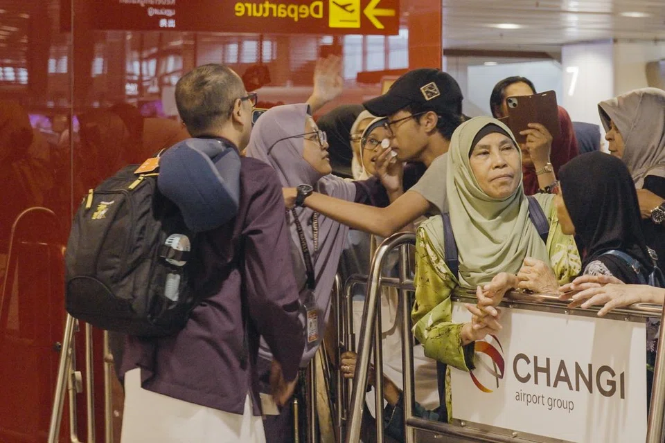 Encik Redzuan Abdullah (kiri) dan isterinya, Cik Marhamah Mohd Sidik, mengucapkan selamat tinggal kepada ahli keluarga yang menghantar mereka di Terminal 1, Lapangan Terbang Changi, pada 22 Mei.
