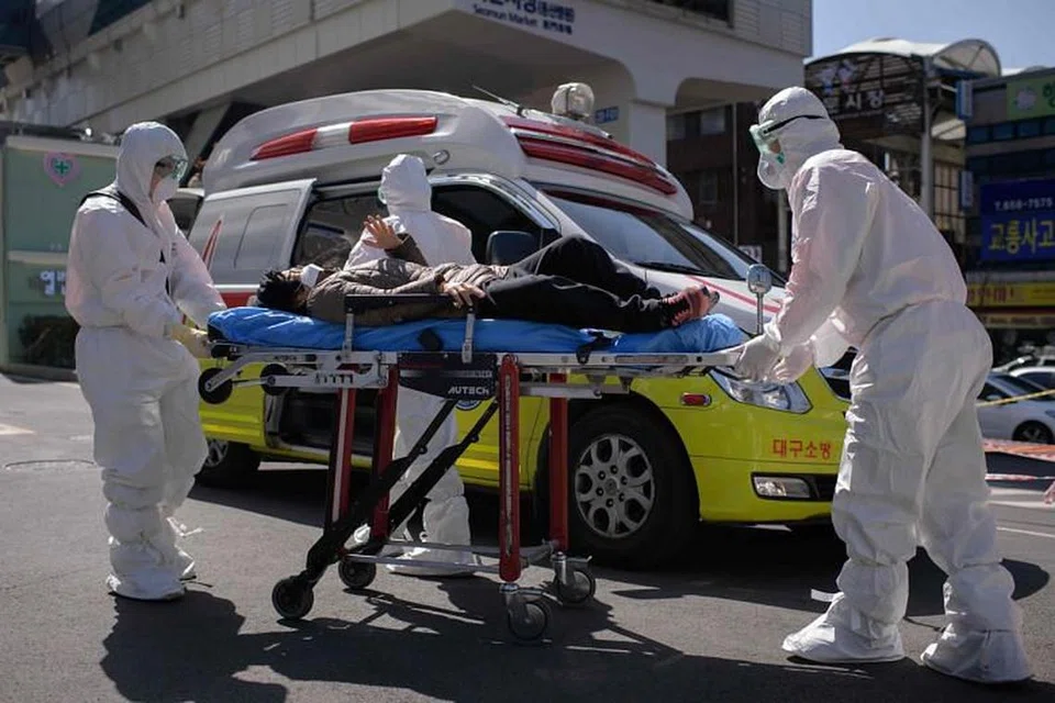 PENGESAHAN PALSU: Pekerja kesihatan dilihat memakai alat pelindungan peribadi sewaktu mengendali seorang pesakit di Hospital Universiti Keimyung, Daegu, pada 12 Mac 2020. FOTO: AFP