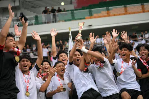 Kapten Meridian, Muhammad Andry Akimi Mahmood, menjulang trofi bersama pasukannya selepas mereka memenangi perlawanan akhir bola sepak lelaki Bahagian B. 