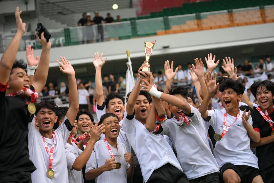 Kapten Meridian, Muhammad Andry Akimi Mahmood, menjulang trofi bersama pasukannya selepas mereka memenangi perlawanan akhir bola sepak lelaki Bahagian B. 