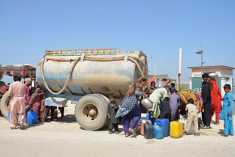 DAPATKAN BEKALAN AIR: Penduduk yang terjejas akibat banjir kilat mengisi air minuman dari lori tangki berhampiran kem sementara di bandar Dera Allah Yar di daerah Jaffarabad, wilayah Balochistan.