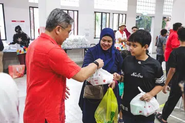 Encik Saktiandi (kiri) mengagih makanan kepada benefisiari di bawah inisiatif Pengedaran Bubur dan Juadah Bulan Ramadan Toa Payoh East di Kelab Masyarakat Toa Payoh Selatan pada 28 Februari.