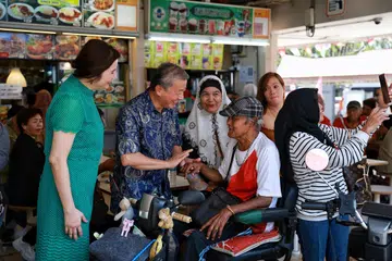 JADI TUMPUAN: Encik  George Goh, yang ditemani isterinya, Cik Lysa Sumali (baju hijau), beramah tamah bersama pesara Encik  Kamis Hassan, 75 tahun, di Pasar dan Pusat Makanan Haig Road pada Ahad.