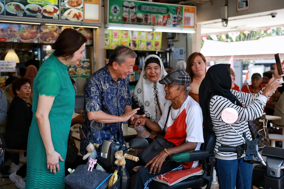 JADI TUMPUAN: Encik  George Goh, yang ditemani isterinya, Cik Lysa Sumali (baju hijau), beramah tamah bersama pesara Encik  Kamis Hassan, 75 tahun, di Pasar dan Pusat Makanan Haig Road pada Ahad.