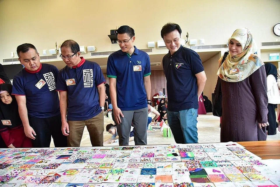 TURUT 'MENGETENGAHKAN BAKAT': Bakal Ketua Eksekutif Muis, Encik Esa Masood (tengah), dan Timbalan Pengarah Eksekutif Kelab Rainbow, Encik Teo Siang Loong, (dua dari kanan) melihat magnet-magnet yang dihasilkan pelajar aLIVE serta kanak-kanak Kelab Rainbow di acara yang berlangsung awal tahun ini. Encik Esa dan Encik Teo turut mereka beberapa magnet. - Foto fail 